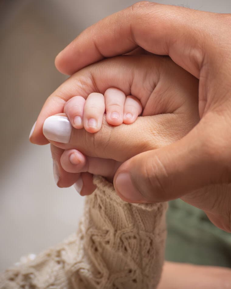 Manos adultas sosteniendo la mano de un recién nacido
